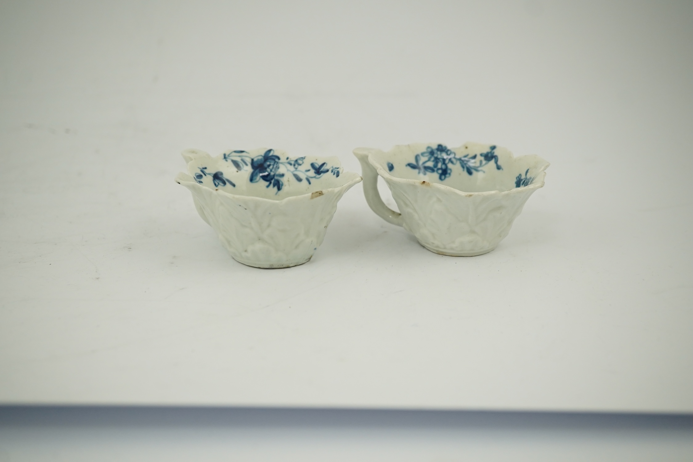 A pair of Worcester blue and white butterboats, c.1758-60, with differing blue and white decoration, 8cm wide. Condition - fair, some chips commensurate with age, one cracked.